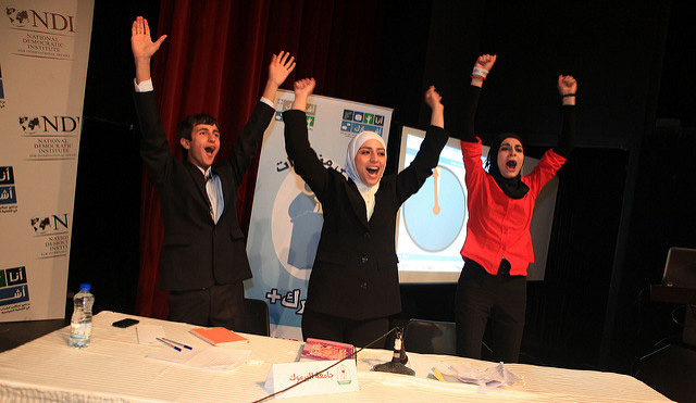Three young people holding their hands up high.