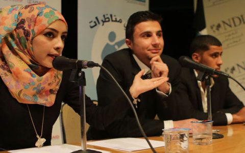 A woman speaking into a microphone during a panel discussion.
