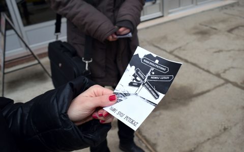 Closeup of a woman's hand, holding a flyer.
